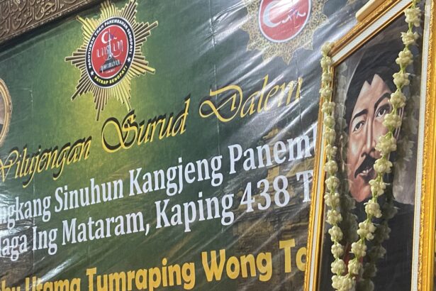 Ceremonial banner with Indonesian text, a star badge, and a portrait framed by a flower garland.