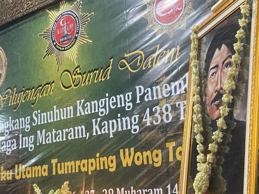 Ceremonial banner with Indonesian text, a star badge, and a portrait framed by a flower garland.
