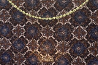 Pale yellow braided cord laid diagonally on a dark blue and brown patterned fabric to show contrast against the textile pattern.