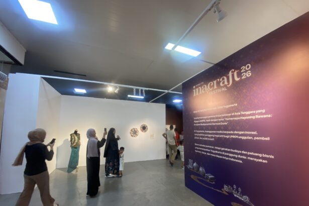 Group of visitors at an exhibition hall, some taking photos, beside a purple wall advertising Inacraft Festival 2026.
