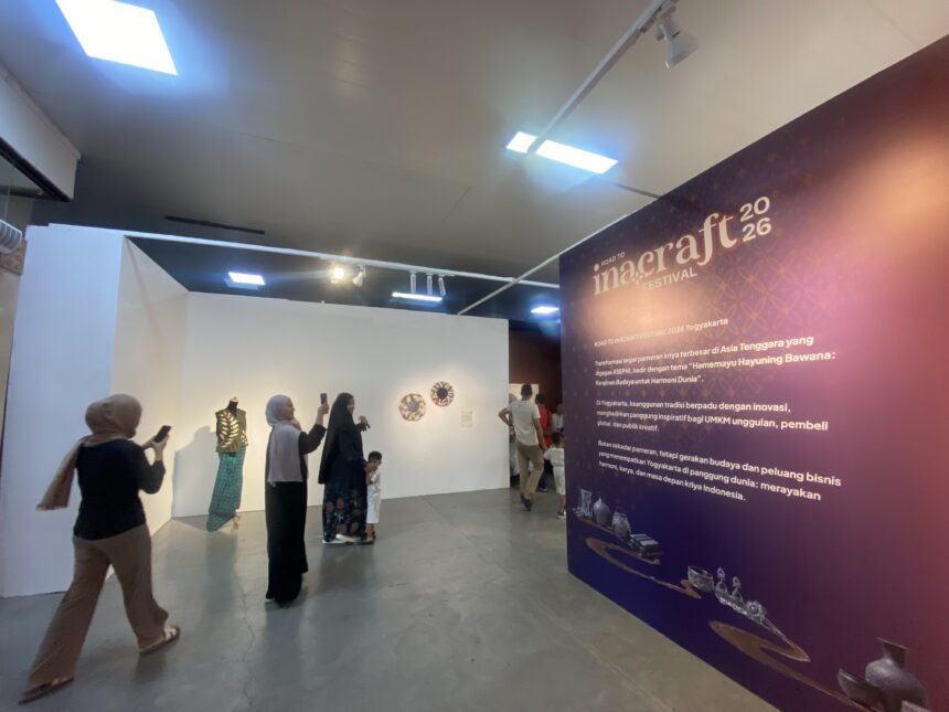 Group of visitors at an exhibition hall, some taking photos, beside a purple wall advertising Inacraft Festival 2026.