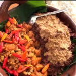 Clay pot with white rice on the side, containing a colorful stir-fry of minced meat and red/yellow peppers on the left and a crumbled topping on the right.