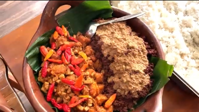Clay pot with white rice on the side, containing a colorful stir-fry of minced meat and red/yellow peppers on the left and a crumbled topping on the right.