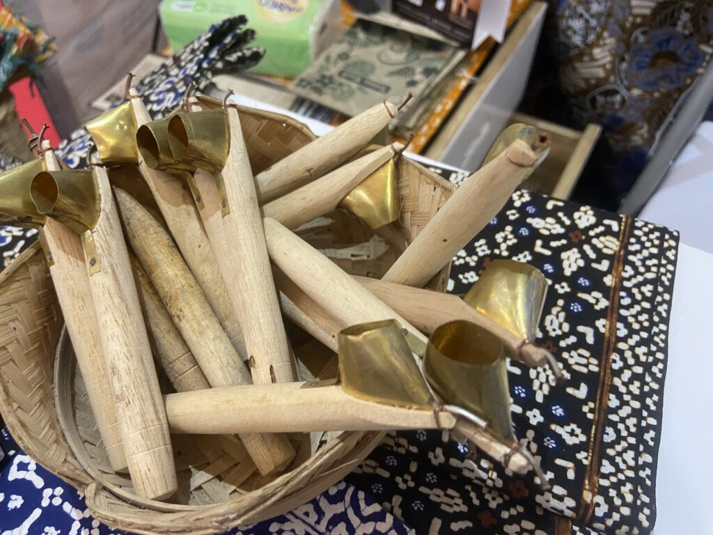 Basket filled with bamboo craft pieces and brass-tipped ends on a patterned tablecloth, seen up close.