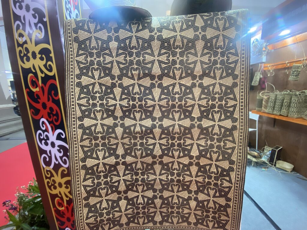 Beige and black geometric woven fabric with a star-like tessellated pattern displayed in a shop window.