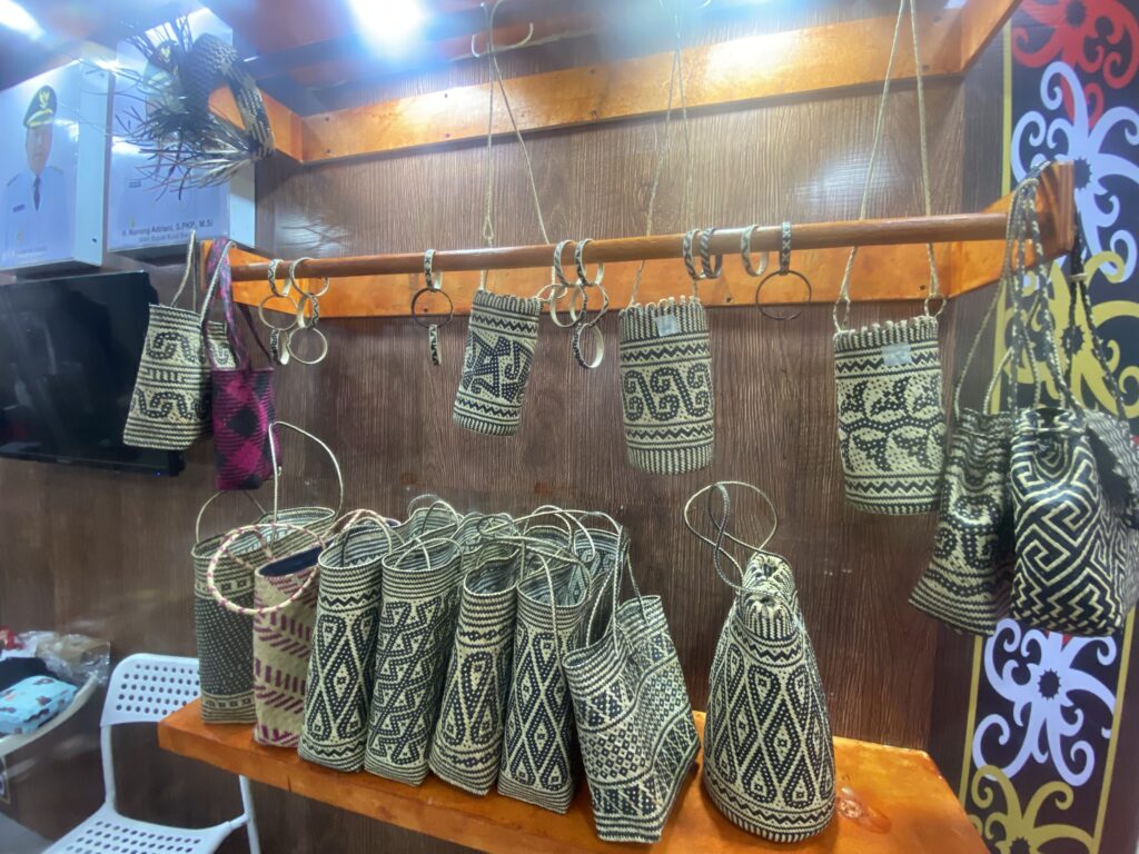 Row of black-and-white patterned woven bags hanging on a wooden rack in a shop display.