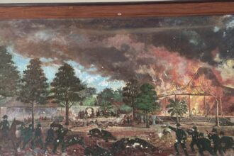 Battle scene in a tropical garden: soldiers fire, people flee, and a thatched pavilion burns in the background.