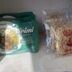 Green Snimi instant noodle package on the left and a clear bag of raw noodles on the right in a freezer.