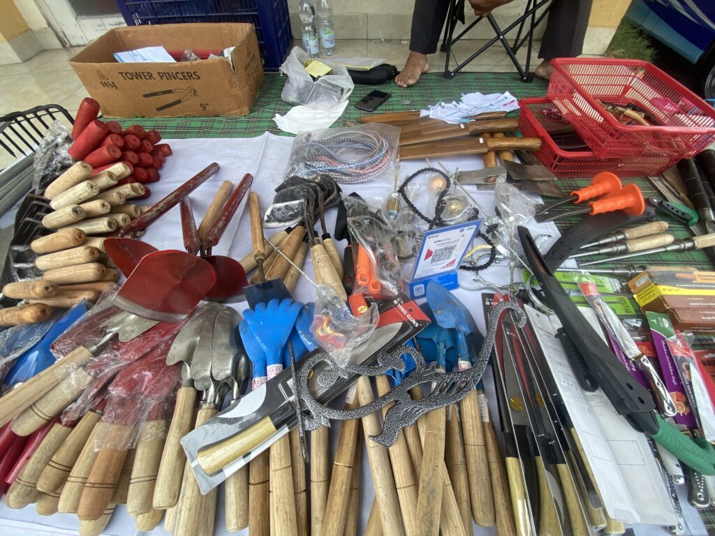 Assorted woodworking tools laid out on a green plaid cloth: chisels, blades, ropes, and a red plastic basket nearby.