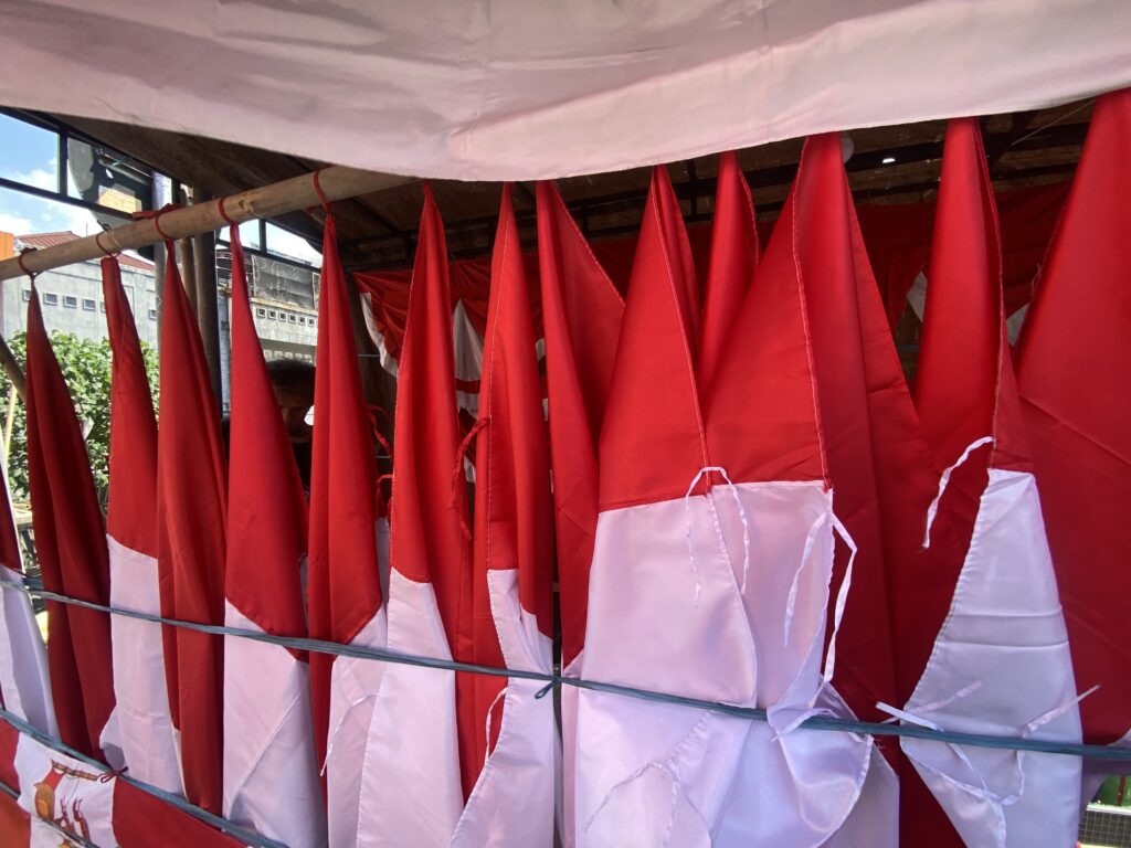 Close-up of red and white fabric banners hanging vertically in an outdoor setup, like festival decorations.