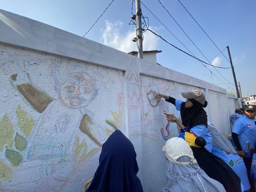 People in blue outfits painting a colorful mural on a white wall outdoors under a clear blue sky.