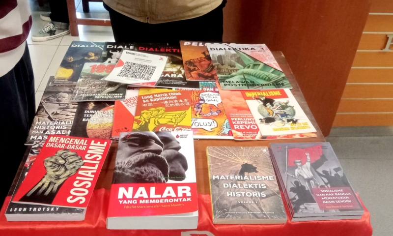 Table with a red cloth displaying many political and historical magazines and books in Indonesian.