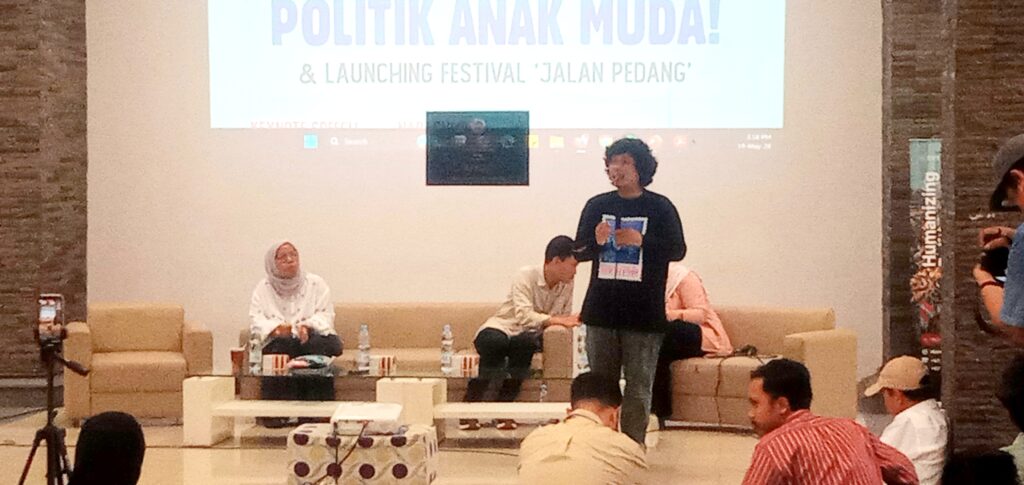 IMG_20260519_151824 - Mabur.co Panel discussion on a stage with three people seated and a speaker standing, projected slide reads POLITIK ANAK MUDA! & LAUNCHING FESTIVAL'JALAN PEDANG'