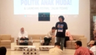 Panel discussion on a stage with three people seated and a speaker standing, projected slide reads POLITIK ANAK MUDA! & LAUNCHING FESTIVAL 'JALAN PEDANG'