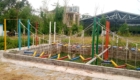 Outdoor obstacle course with colorful planks and ropes suspended between tall posts in a yard.