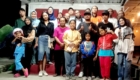 Group of diverse people posing together on a stage indoors, smiling at the camera.