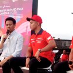 Panel of four men seated on stage during a MotoGP event, with a pink banner in the background reading 'PERTAMINA GRAND PRIX OF INDONESIA 2026'. One man speaks into a microphone while the others wear red Honda-branded shirts or casual attire.