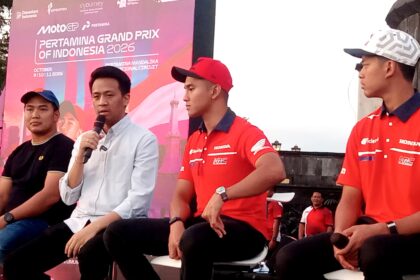 Panel of four men seated on stage during a MotoGP event, with a pink banner in the background reading 'PERTAMINA GRAND PRIX OF INDONESIA 2026'. One man speaks into a microphone while the others wear red Honda-branded shirts or casual attire.