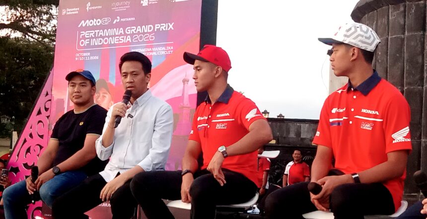 Panel of four men seated on stage during a MotoGP event, with a pink banner in the background reading 'PERTAMINA GRAND PRIX OF INDONESIA 2026'. One man speaks into a microphone while the others wear red Honda-branded shirts or casual attire.