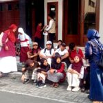 Group of children with backpacks sitting on steps outside a building, waiting or resting.