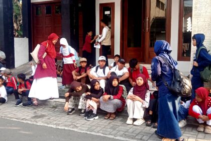 Group of children with backpacks sitting on steps outside a building, waiting or resting.