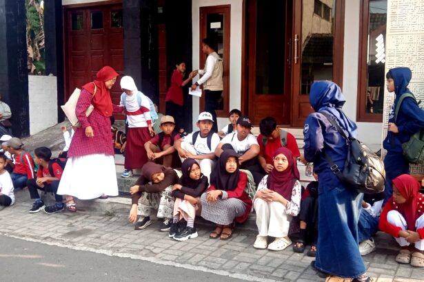 Group of children with backpacks sitting on steps outside a building, waiting or resting.
