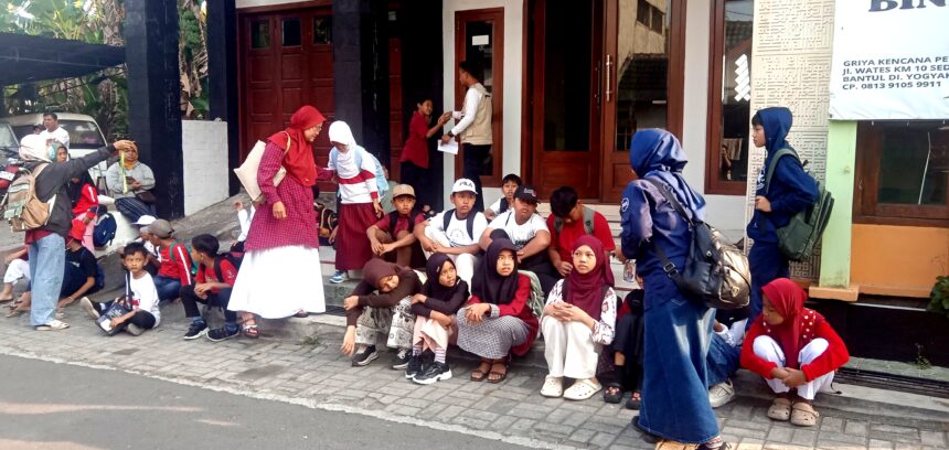 Group of children with backpacks sitting on steps outside a building, waiting or resting.