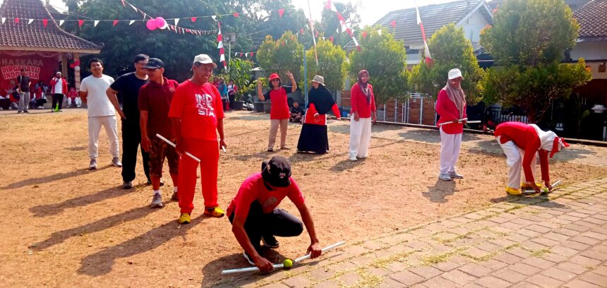 Group of people in red and white outfits playing a croquet-style game on a dusty ground while others watch at a festival, with bunting overhead.