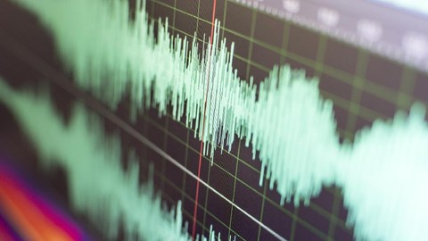 Close-up of a teal audio waveform on a dark grid background with a red cursor line.