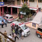 School courtyard with multiple ambulances and staff gathered near the building entrance.
