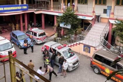 School courtyard with multiple ambulances and staff gathered near the building entrance.