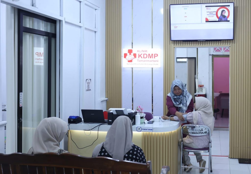 IMG_3467 - Mabur.co Reception desk in a clinic where a staff member in a hijab assists a patient; KDMP clinic sign visible behind them.