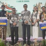 Group on stage at an awards ceremony holding oversized prize cheques, showing Rp 20,000,000 and Rp 15,000,000 against a decorative backdrop.