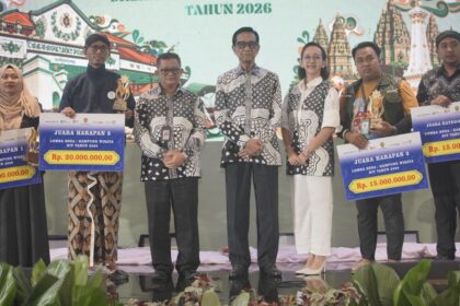 Group on stage at an awards ceremony holding oversized prize cheques, showing Rp 20,000,000 and Rp 15,000,000 against a decorative backdrop.