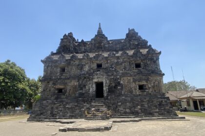 Ancient stone temple with a tiered roof and small rectangular openings, set under a clear blue sky.