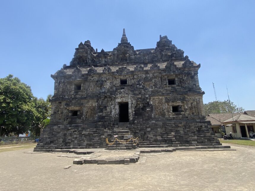 Ancient stone temple with a tiered roof and small rectangular openings, set under a clear blue sky.