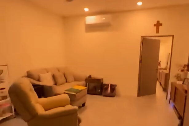 Cozy living room with beige sofa and matching recliner, small coffee table, and cross hanging above a doorway on a warm-lit wall