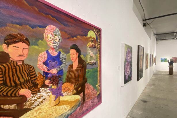 Large colorful painting of people in striped clothing hanging on a white gallery wall, with a pink frame; other artworks line the corridor.