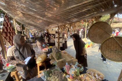 Market stall with women in hijabs selling snacks in clear bags under a plastic-covered roof.