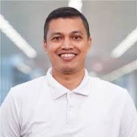 Portrait of a man in a white polo shirt smiling at the camera in an indoor setting with a blurred background.
