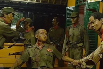 Diorama of soldiers in green uniforms; a man seated with arms extended while others surround him.