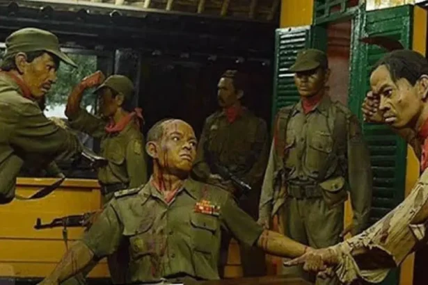 Diorama of soldiers in green uniforms; a man seated with arms extended while others surround him.