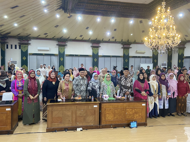 Group of people in traditional attire posing together in a banquet hall for a formal event.