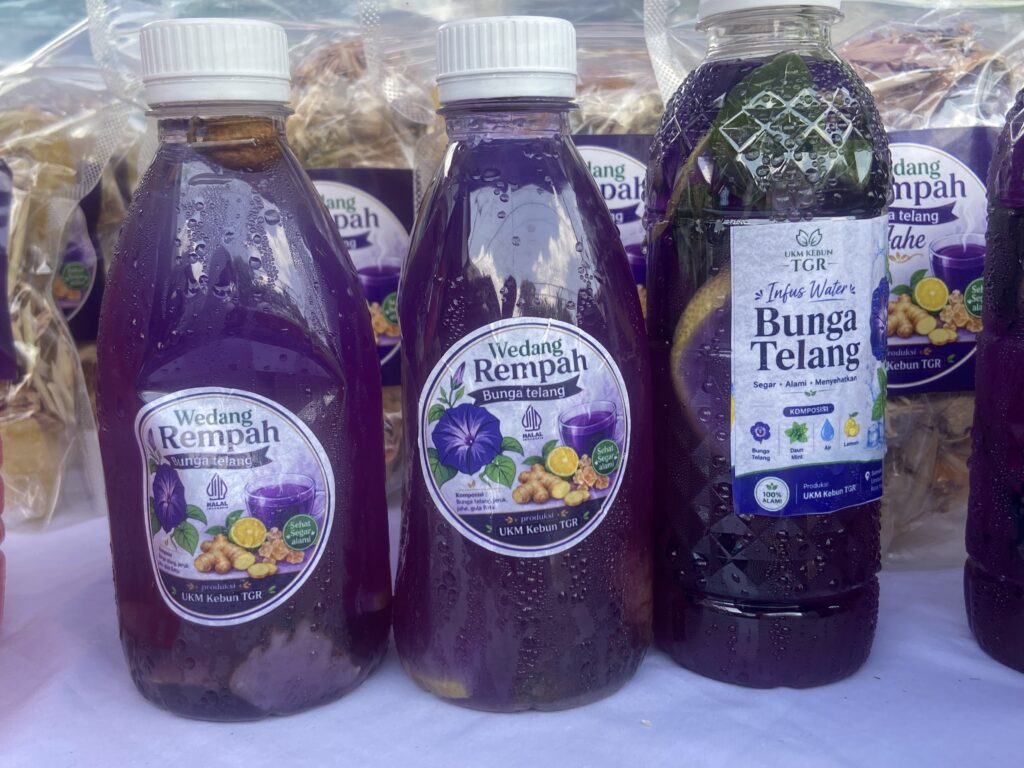 IMG_5613 - Mabur.co Purple bottled drinks with condensation and labels reading Wedang Rempah Bunga Telang, bright purple beverage in plastic bottles on a display shelf.