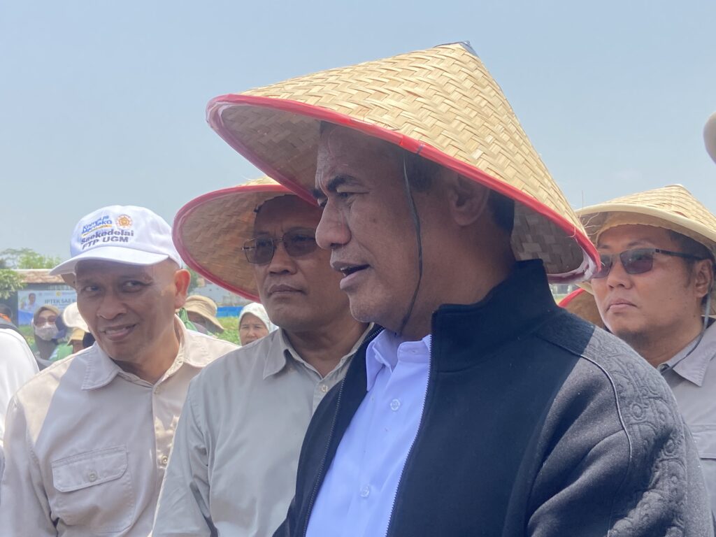 IMG_5748 - Mabur.co Group of men wearing traditional conical straw hats at an outdoor daytime gathering, with blue sky in the background and one man in a black jacket in the foreground.