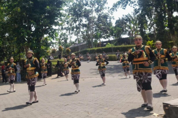 Group of dancers in green and gold traditional costumes performing a parade on a sunny day in a park or square.