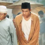 Two men in traditional clothing walk through a crowded outdoor market with umbrellas in the background.