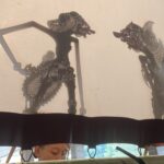 Two intricately carved dragon silhouettes hanging as wall art, with a person visible below.