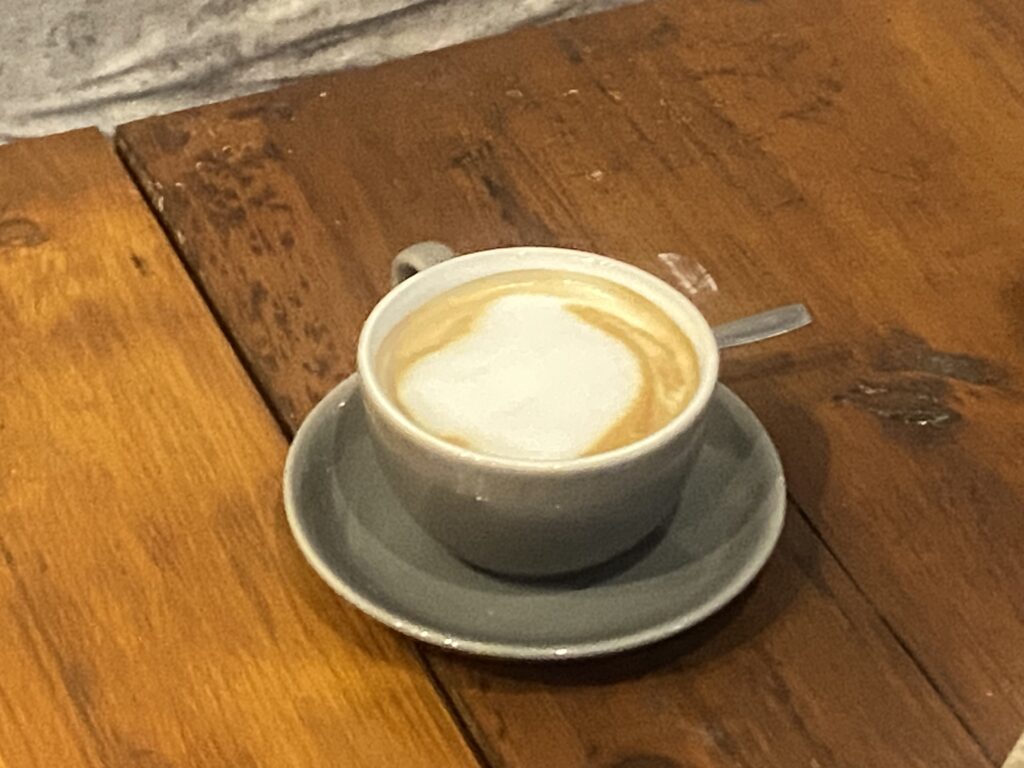Top-down view of a ceramic cup with latte crema on a saucer, placed on a wooden table.