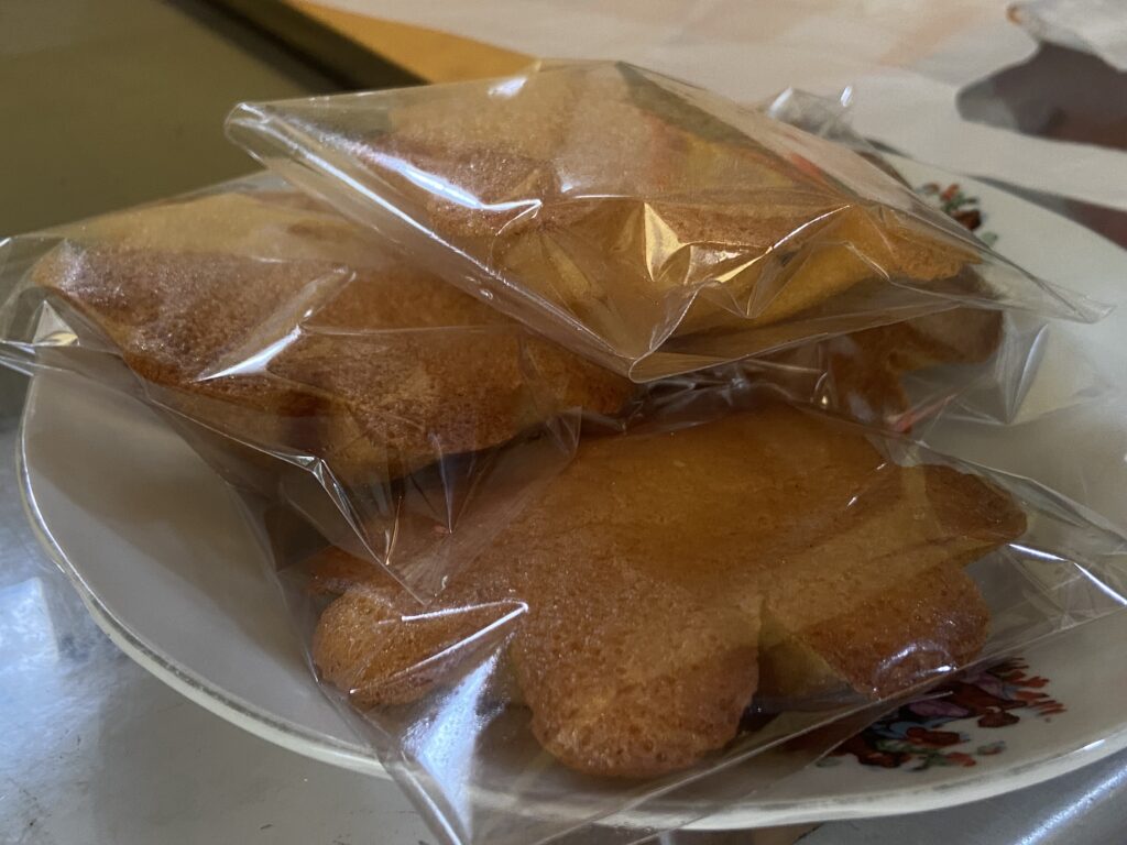 IMG_7346 - Mabur.co Stack of golden cookies wrapped in clear plastic bags resting on a white plate.
